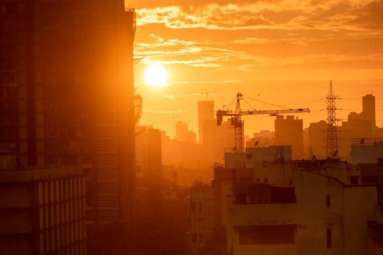 Silhueta de um guindaste e um edifício ao pôr do sol, calor